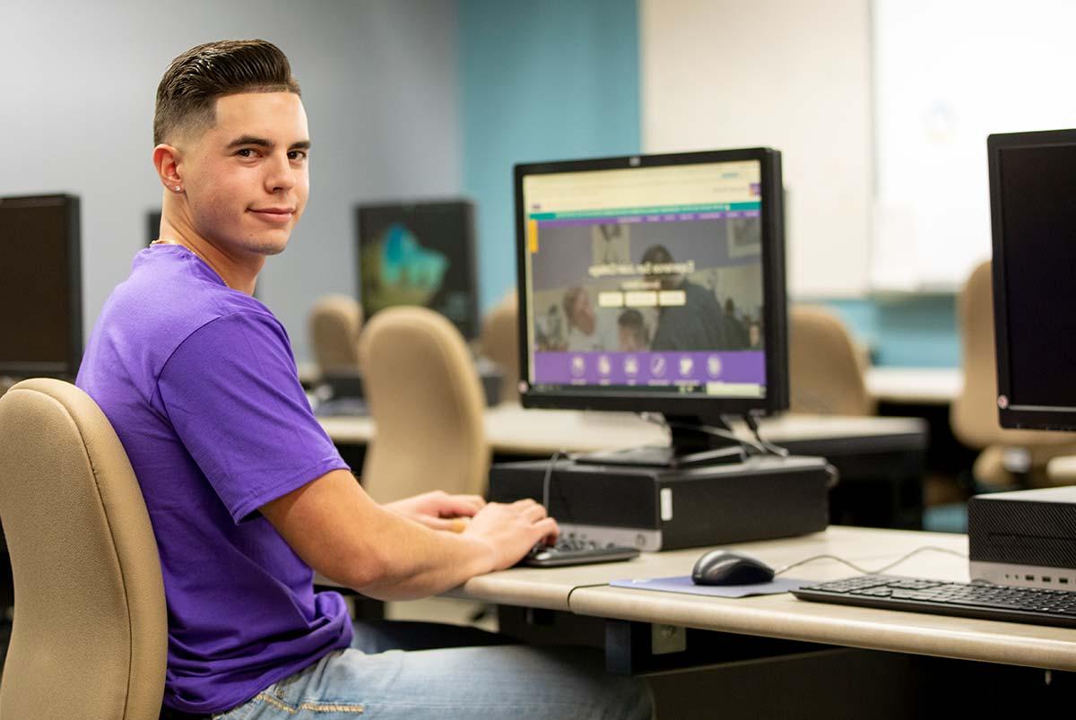 San Juan College IT student sitting in Computer Lab.